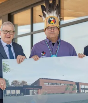 image of three people in front of a building holding architectural rendering of a building