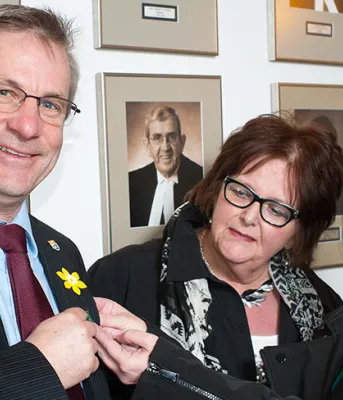 Minister Henderson shows dafidil on lapel and thw people look on.