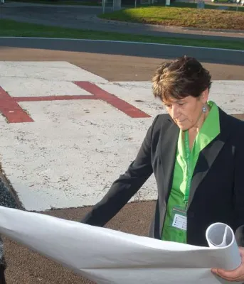 Minister Biggar and Minister henderson and one other person review construction plans near the PCH Helipad