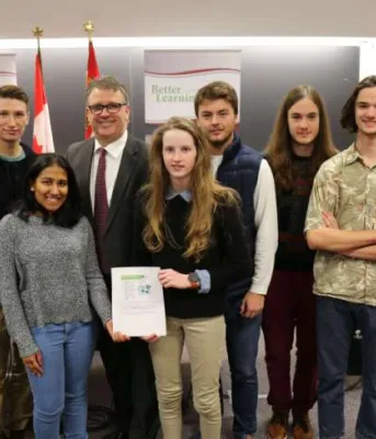 Minister Curries stands with a group of high school students