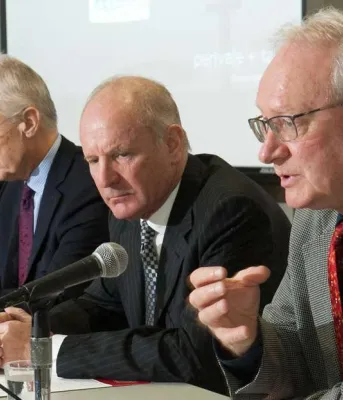 Premier MacLauchlan and three others sit at a table discussing the review