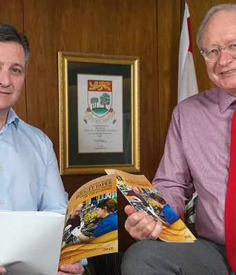 Photo shows Minister Heath MacDonald and Premier Wade MacLauchlan holding copies of the 2018-19 operating budget.