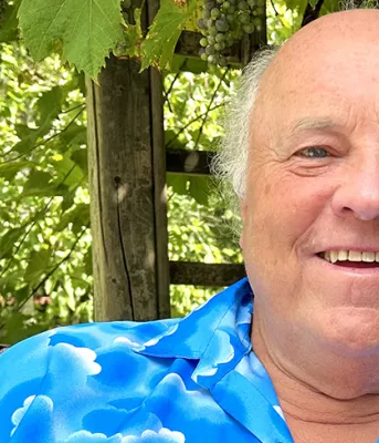 image d'une tête et d'épaules représentant une personne avec des arbustes verts en arrière-plan