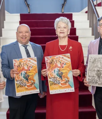 image of four people inside a buidling standing shoulder to shoulder holding posters with a staircase in the background