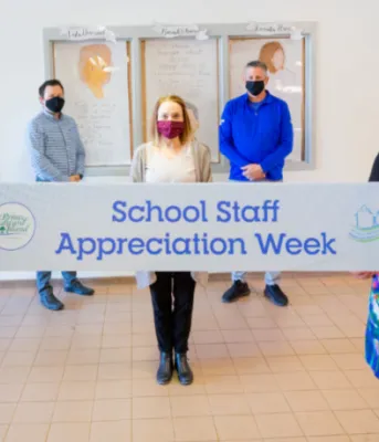 image of two people holding a sign and other people standing behind them