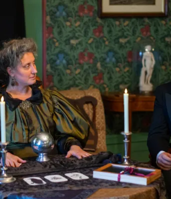 image de deux personnes vêtues de vêtements du XIXe siècle, assises à une table