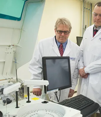 Four people looking at a computer screen in a science laboratory