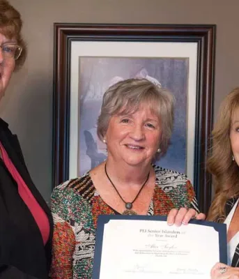 Three women holding certificate for senior of the year award