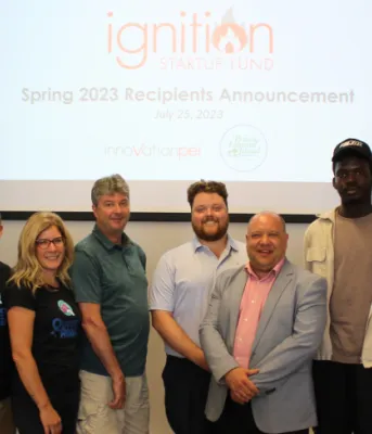 image of a group of people standing shoulder to shoulder in front of stand up banners and a screen