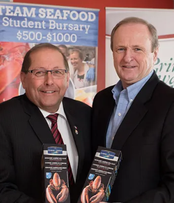 Four people standing in Team Seafood Student Bursary signs.