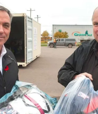 Two men holding bags of textiles for recycling