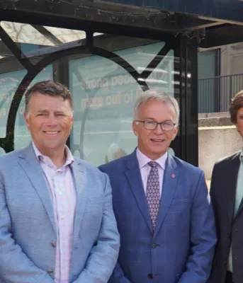 Five people standing shoulder to shoulder in front of a bus stop