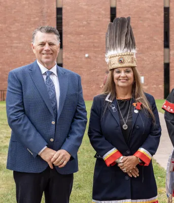 image of four people standing shoulder to shoulder with a brick building in the background