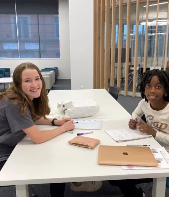 Tutor and young child sit together at a table