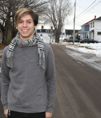 Tyler Murnaghan stands alone on a snowy city street smiling at the camera.