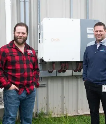 image of four people standing in front of some energy efficiency equipment outside a community rink