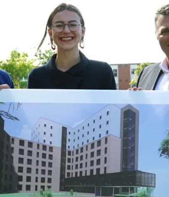 three people holding a picture of a building