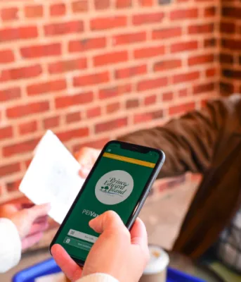 image of person showing an information card and viewing a pas on a cell phone