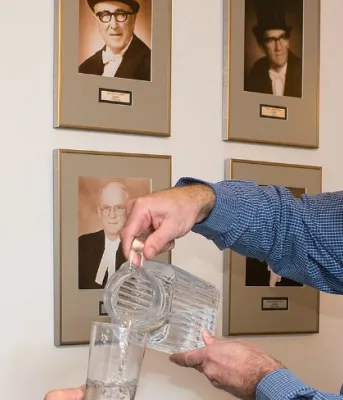 Photo shows Dean Stewart pouring a glass of water for Minister Robert Henderson