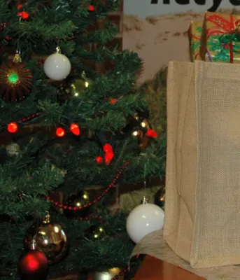 a Christmas tree beside with a shopping bag full of wrapped gifts