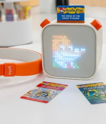 image of orange coloured headphones and small cube audio player on a small round table