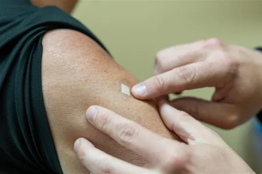 A doctor applies a bandaid to a person&#039;s arm after vaccination.
