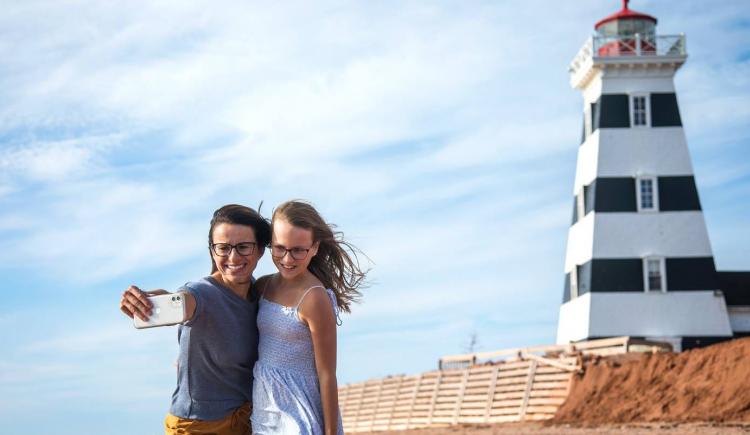 two people taking a photo in front of a lighthouse