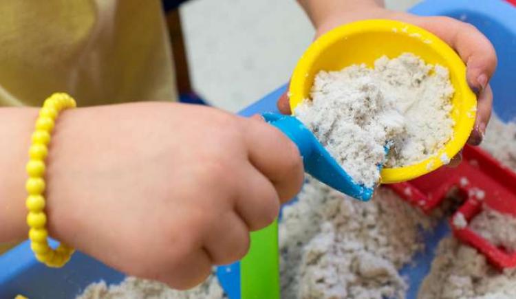 Image of a child's hand playing in a sand table