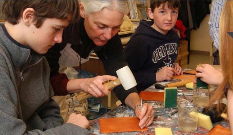 Female demonstrating leather craft to youth