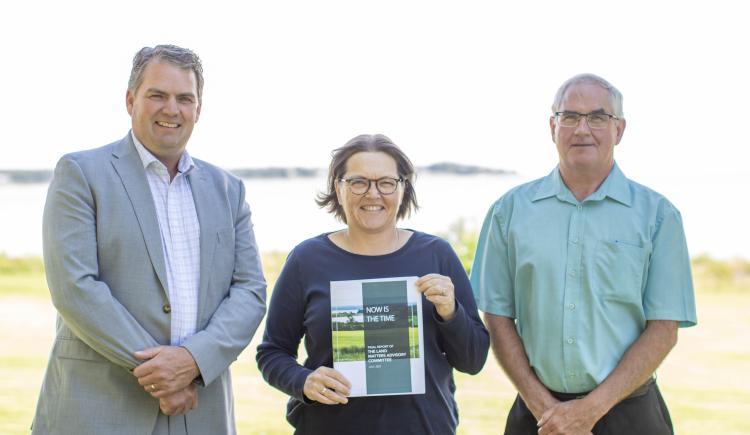 image of three people standing shoulder to shoulder and middle person holding the booklet report