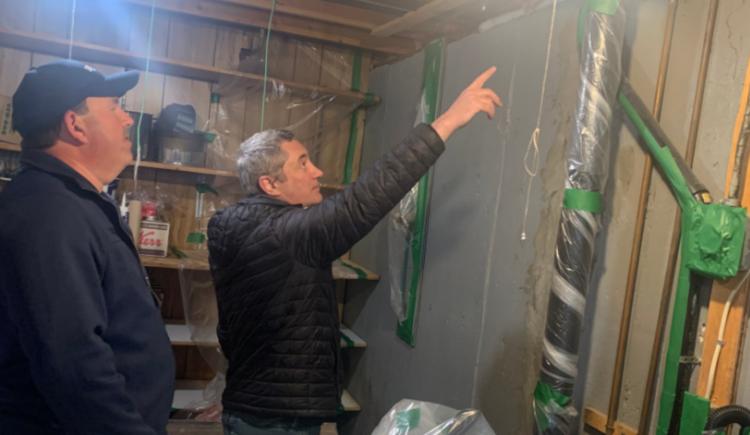 Photo shows a man installing insulation in a home