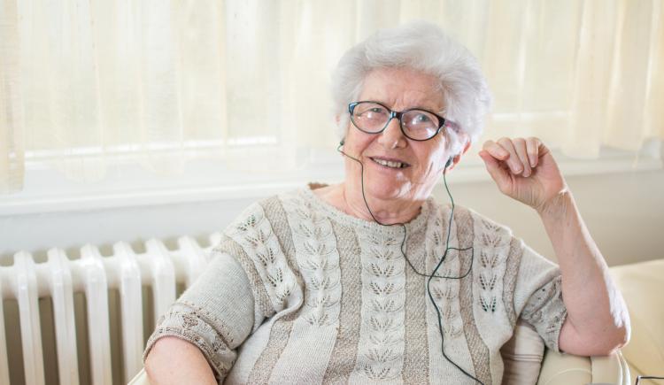 Female senior using headphones to listen to music device