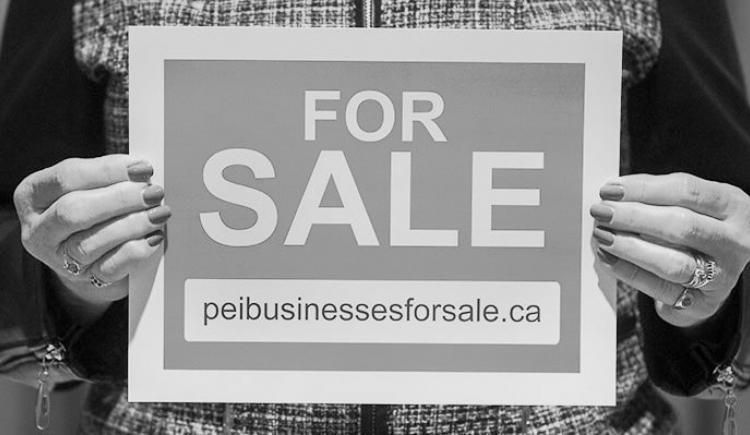 Image of woman holding a FOR SALE sign that lists the peibusinessesforsale.ca website address 