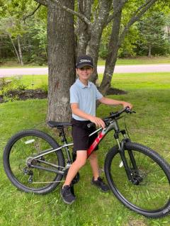 Grade 6 student Colin Joseph MacCormac sitting on his bike outdoors